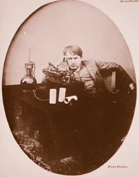 Thomas A. Edison sitting by his improved machine, 1889